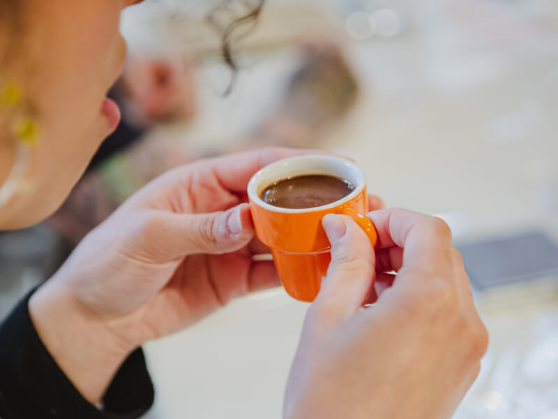 A person is holding a small orange cup filled with hot chocolate